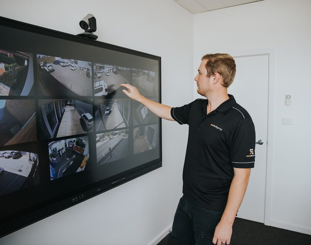 Technician from Next Tech Group monitoring CCTV footage on a large screen