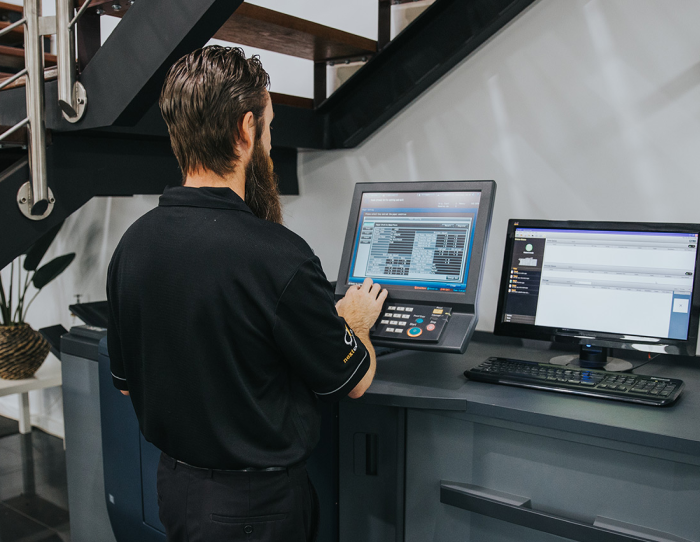 print-software-700 Man operating a large printer with a touchscreen interface in an office