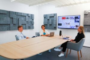 Office meeting room with screen and audio visual accessories and workers having a meeting
