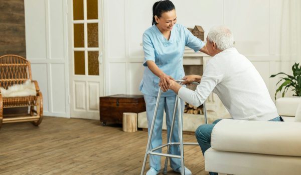 healthcare worker helping elderly person out of a chair
